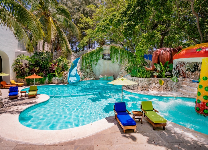 Kids pool with a water slide and cenote-themed waterfall at Oasis Palm