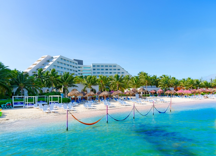 Oasis Palm hotel beach with hammocks over the turquoise water and loungers under palapas